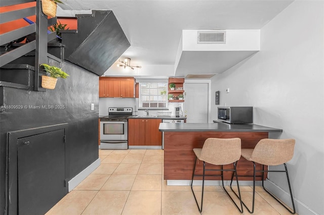 938 SW 6th St Unit 8, Miami, FL 33130 - kitchen with appliances with stainless steel finishes, dark countertops, a peninsula, a sink, and brown cabinetry