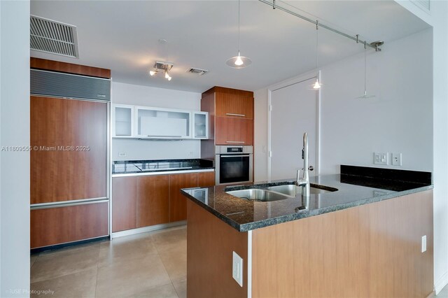 17201 Collins Ave Unit 2006, Sunny Isles Beach, FL 33160 - kitchen featuring oven, brown cabinetry, paneled built in fridge, a sink, and a peninsula