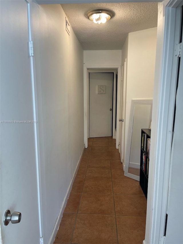 1770 NE 191st St Unit 316-1, Miami, FL 33179 - hallway featuring a textured ceiling, tile patterned flooring, and baseboards