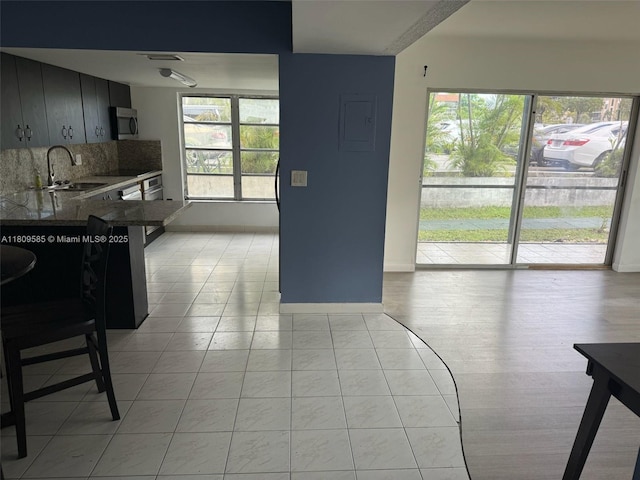 4168 Inverrary Dr Unit 111, Lauderhill, FL 33319 - kitchen with stainless steel microwave, electric panel, decorative backsplash, a breakfast bar, and a peninsula
