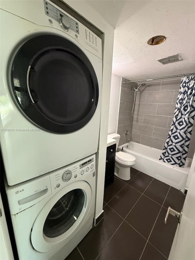 4168 Inverrary Dr Unit 111, Lauderhill, FL 33319 - laundry area with stacked washer / drying machine, a textured ceiling, and dark tile patterned flooring