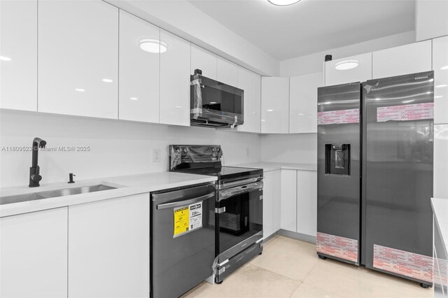 2300 Diana Dr Unit 302, Hallandale Beach, FL 33009 - kitchen with stainless steel appliances, modern cabinets, white cabinets, a sink, and light countertops