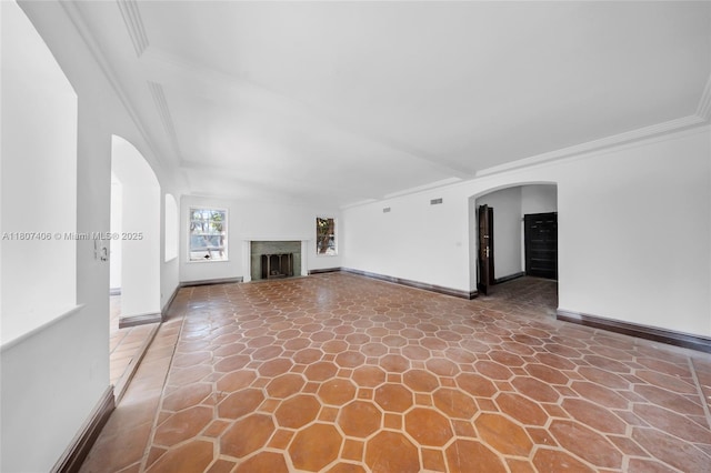5757 Alton Rd, Miami Beach, FL 33140 - unfurnished living room with arched walkways, ornamental molding, a fireplace, baseboards, and stone finish floors