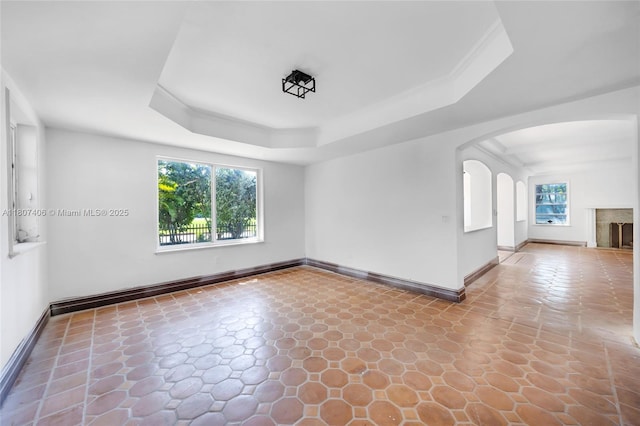 5757 Alton Rd, Miami Beach, FL 33140 - unfurnished room with baseboards, arched walkways, a tray ceiling, and stone finish flooring