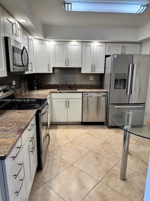 251 174th St Unit 1112, Sunny Isles Beach, FL 33160 - kitchen featuring appliances with stainless steel finishes, a sink, light tile patterned floors, decorative backsplash, and dark stone counters
