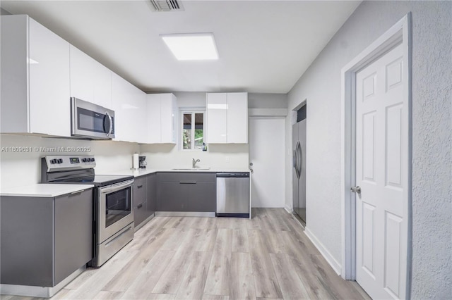 6039 SW 38th St, Miramar, FL 33023 - kitchen featuring appliances with stainless steel finishes, light wood-style flooring, white cabinets, light countertops, and modern cabinets