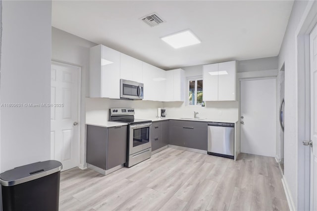 6039 SW 38th St, Miramar, FL 33023 - kitchen featuring appliances with stainless steel finishes, light wood-type flooring, light countertops, and white cabinetry