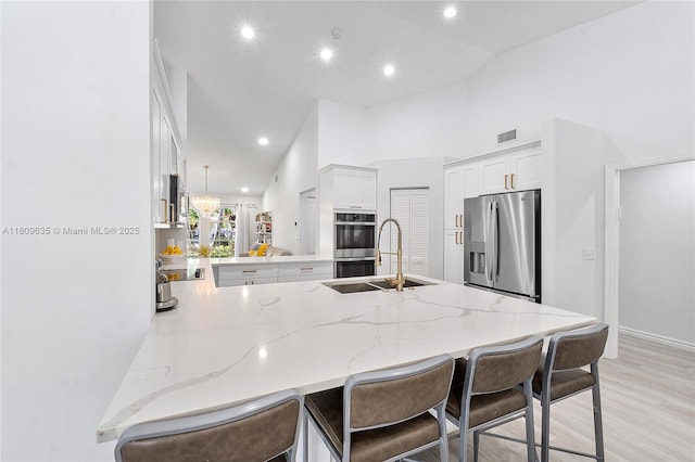 4647 NW 98th Ln, Coral Springs, FL 33076 - kitchen with appliances with stainless steel finishes, a peninsula, light stone counters, a breakfast bar area, and recessed lighting