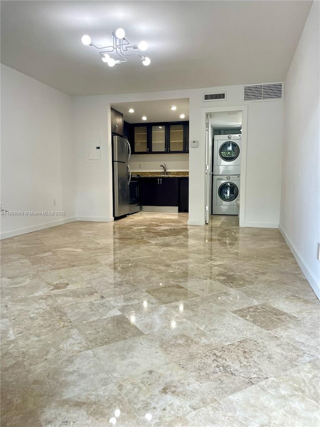 3025 Mary St Unit 5, Miami, FL 33133 - unfurnished living room with stacked washer and clothes dryer, baseboards, a chandelier, and light marble finish floors