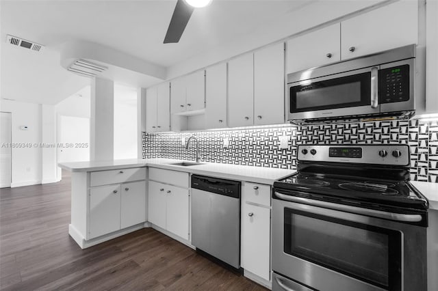1051 Meridian Ave Unit 1-A, Miami Beach, FL 33139 - kitchen featuring stainless steel appliances, a peninsula, light countertops, white cabinets, and decorative backsplash