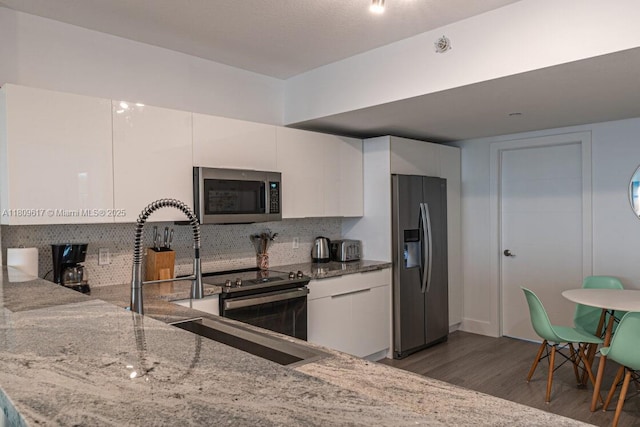 17050 N Bay Rd Unit 401, Sunny Isles Beach, FL 33160 - kitchen with stainless steel appliances, wood finished floors, light stone countertops, and decorative backsplash
