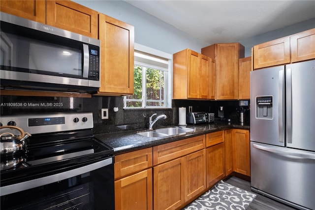 37 NW 47th Ter, Miami, FL 33127 - kitchen with appliances with stainless steel finishes, a sink, backsplash, dark stone countertops, and wood finished floors
