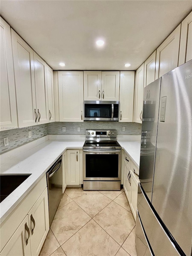 3536 NE 168th St Unit 201, North Miami Beach, FL 33160 - kitchen with stainless steel appliances, light countertops, decorative backsplash, light tile patterned flooring, and white cabinetry