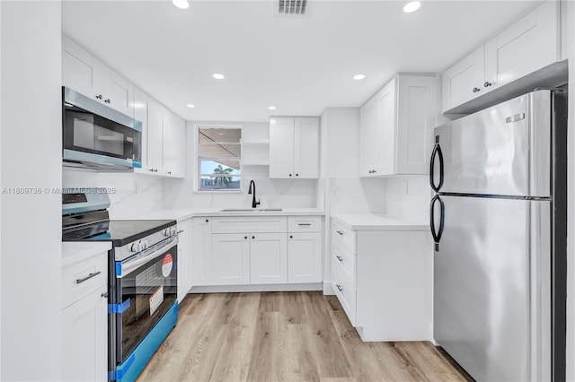 816 NW 87th Ave Unit 502, Miami, FL 33172 - kitchen with appliances with stainless steel finishes, a sink, light wood-type flooring, white cabinetry, and recessed lighting