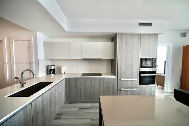2900 NE 7th Ave Unit 2105, Miami, FL 33137 - kitchen featuring wall oven, modern cabinets, a sink, cooktop, and black microwave