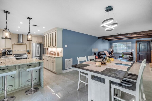 641 SW 50th Ave, Margate, FL 33068 - kitchen with appliances with stainless steel finishes, wall chimney exhaust hood, a kitchen breakfast bar, a chandelier, and light stone counters