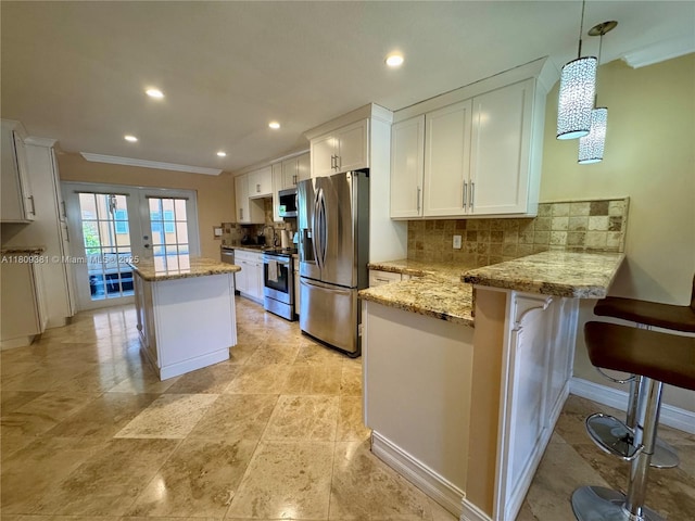 2200 Monroe St Unit 33, Hollywood, FL 33020 - kitchen featuring appliances with stainless steel finishes, a peninsula, white cabinetry, decorative backsplash, and ornamental molding