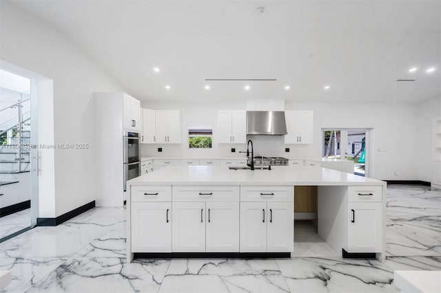 5121 SW 210th Ter, Southwest Ranches, FL 33332 - kitchen featuring light marble finish flooring, stainless steel double oven, a sink, wall chimney range hood, and white cabinetry