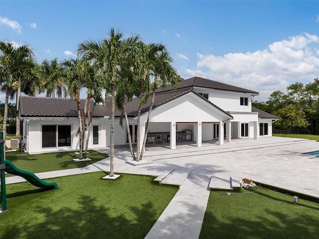 5121 SW 210th Ter, Southwest Ranches, FL 33332 - rear view of house featuring stucco siding, a lawn, a playground, and a tile roof
