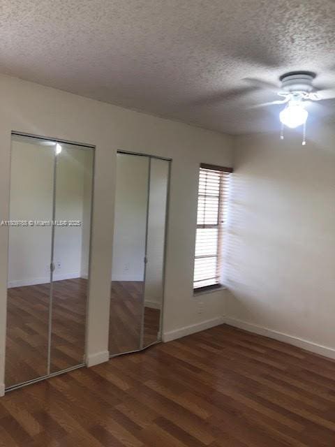 9909 Twin Lakes Dr Unit 26-F, Coral Springs, FL 33071 - unfurnished bedroom with two closets, a textured ceiling, wood finished floors, baseboards, and a ceiling fan