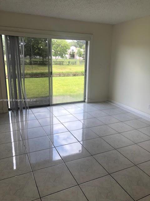 9909 Twin Lakes Dr Unit 26-F, Coral Springs, FL 33071 - unfurnished room with light tile patterned floors, a textured ceiling, and baseboards