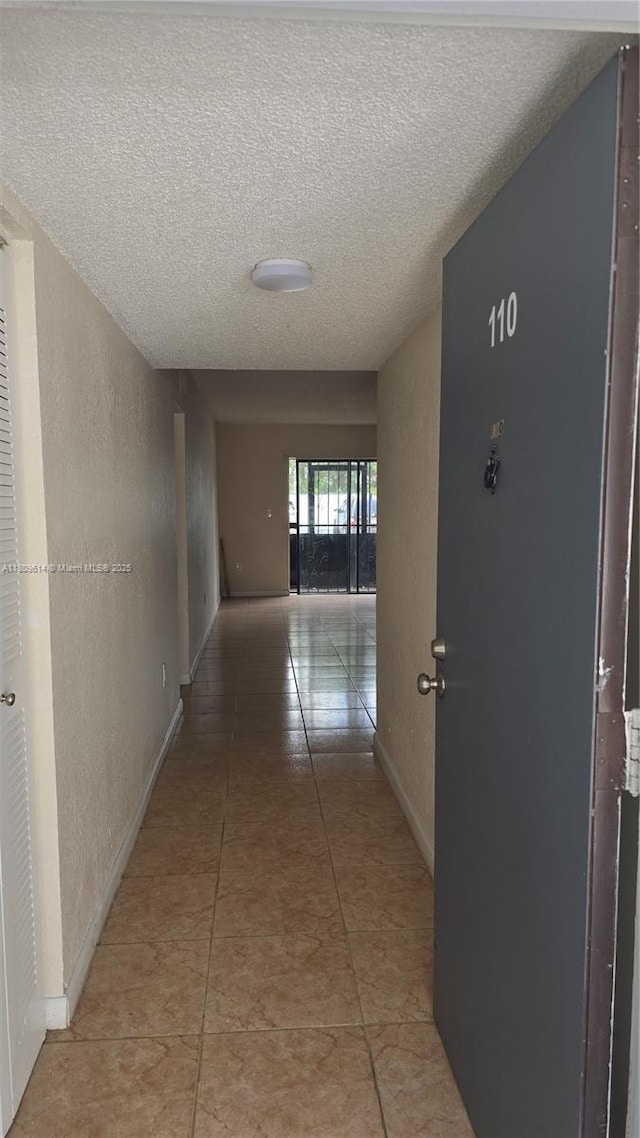 13500 NE 3rd Ct Unit 110, North Miami, FL 33161 - hallway featuring a textured ceiling, light tile patterned floors, a textured wall, and baseboards