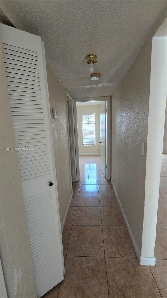 13500 NE 3rd Ct Unit 110, North Miami, FL 33161 - hall with baseboards, a textured ceiling, tile patterned floors, and a textured wall