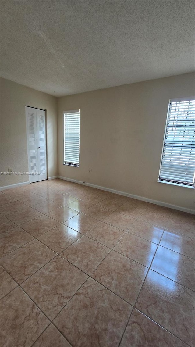 13500 NE 3rd Ct Unit 110, North Miami, FL 33161 - tiled spare room with a textured ceiling and baseboards