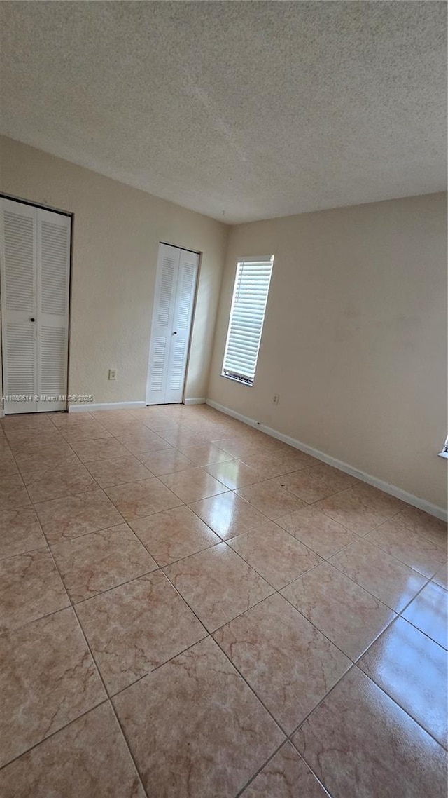 13500 NE 3rd Ct Unit 110, North Miami, FL 33161 - unfurnished bedroom with multiple closets, light tile patterned floors, a textured ceiling, and baseboards