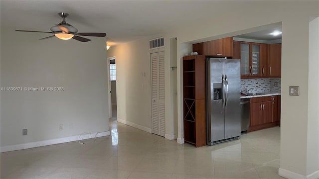 421 NE 1st St Unit 119, Hallandale Beach, FL 33009 - kitchen with stainless steel appliances, light countertops, ceiling fan, decorative backsplash, and glass insert cabinets