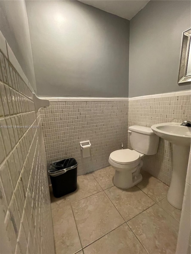 421 NE 1st St Unit 119, Hallandale Beach, FL 33009 - half bathroom with a wainscoted wall, toilet, tile walls, and tile patterned floors