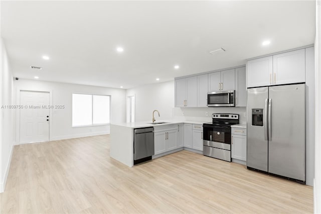 18011 NW 48th Pl, Miami Gardens, FL 33055 - kitchen featuring appliances with stainless steel finishes, a sink, a peninsula, light wood-style flooring, and light countertops