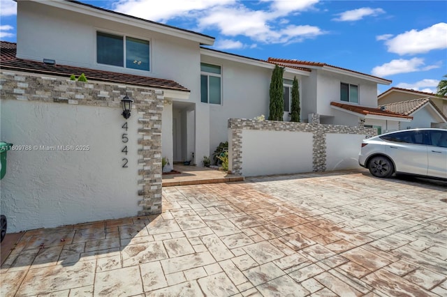 4542 SW 143rd Ct W, Miami, FL 33175 - view of front of home with stucco siding, a tiled roof, stone siding, and a patio