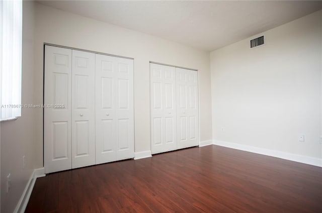 50 SW Menores Ave Unit 732, Coral Gables, FL 33134 - unfurnished bedroom featuring two closets, dark wood-style floors, and baseboards
