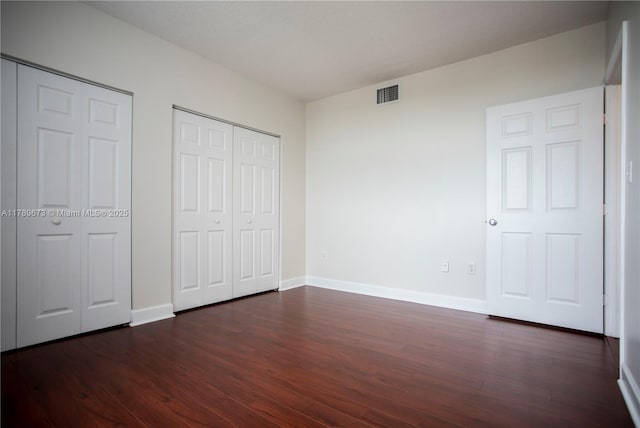 50 SW Menores Ave Unit 732, Coral Gables, FL 33134 - unfurnished bedroom featuring two closets, dark wood-style floors, and baseboards