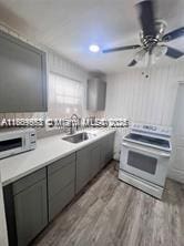 2325 Hayes St, Hollywood, FL 33020 - kitchen featuring white electric range oven, gray cabinets, wood finished floors, ceiling fan, and a sink