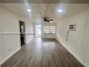 2325 Hayes St, Hollywood, FL 33020 - empty room with wood finished floors, baseboards, a ceiling fan, and a wall unit AC