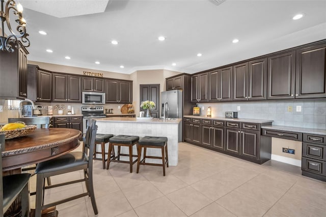 9003 Alexandra Cir, Wellington, FL 33414 - kitchen with appliances with stainless steel finishes, ornamental molding, dark brown cabinetry, decorative backsplash, and a kitchen breakfast bar