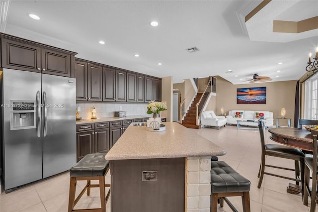 9003 Alexandra Cir, Wellington, FL 33414 - kitchen featuring stainless steel fridge with ice dispenser, a breakfast bar area, open floor plan, light tile patterned floors, and a kitchen island