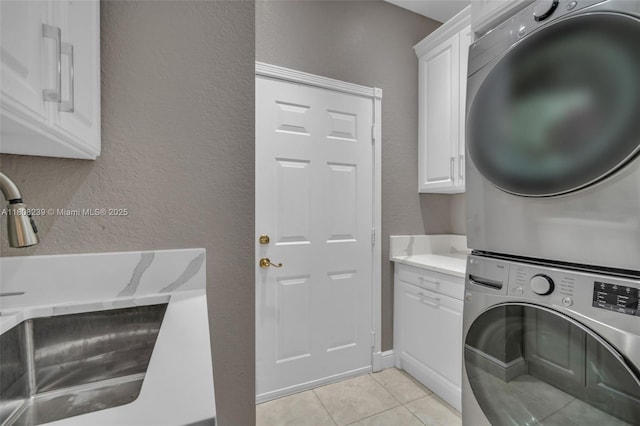 9003 Alexandra Cir, Wellington, FL 33414 - laundry room with stacked washer and clothes dryer, cabinet space, light tile patterned flooring, and a textured wall