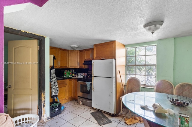 226 NW 16th Ave, Miami, FL 33125 - kitchen featuring freestanding refrigerator, electric range, under cabinet range hood, a textured ceiling, and light tile patterned flooring