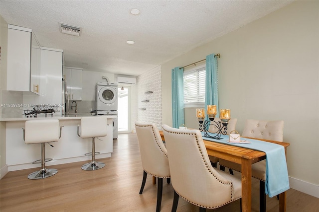 5920 SW 94th Ave, Miami, FL 33173 - dining space with estacked washer and dryer, light wood-type flooring, baseboards, and a textured ceiling