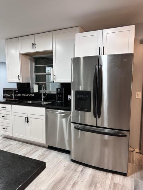 2359 Gabriel Ln, West Palm Beach, FL 33406 - kitchen featuring stainless steel appliances, a sink, light wood finished floors, and white cabinets
