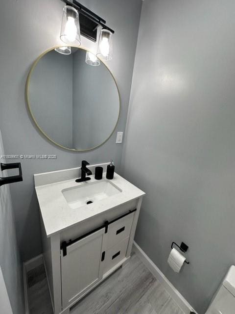 2359 Gabriel Ln, West Palm Beach, FL 33406 - half bathroom featuring vanity, baseboards, wood finished floors, and toilet