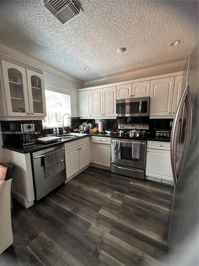 10054 SW 163rd Ct, Miami, FL 33196 - kitchen with stainless steel appliances, dark countertops, glass insert cabinets, a textured ceiling, and white cabinetry