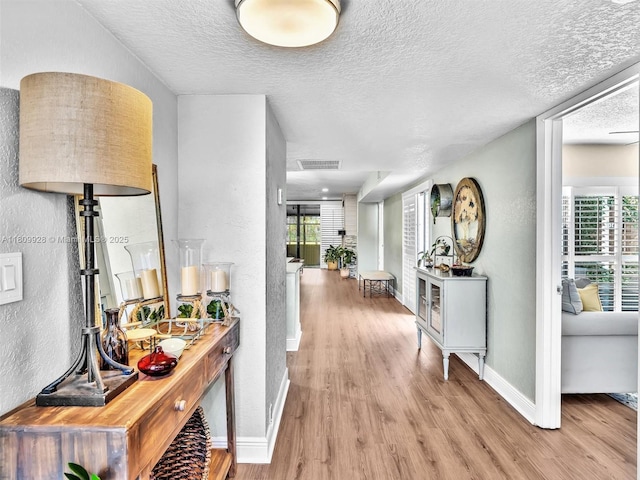 1489 Fairway Rd, Pembroke Pines, FL 33026 - hall with light wood-style flooring, healthy amount of natural light, a textured ceiling, baseboards, and a textured wall