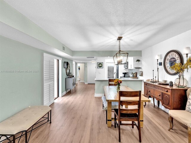 1489 Fairway Rd, Pembroke Pines, FL 33026 - dining room with light wood-type flooring, a textured ceiling, and baseboards