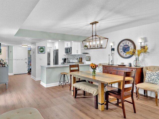 1489 Fairway Rd, Pembroke Pines, FL 33026 - dining space featuring light wood-style floors, baseboards, and a textured ceiling