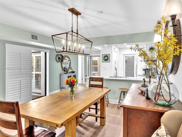 1489 Fairway Rd, Pembroke Pines, FL 33026 - dining room featuring light wood finished floors, a chandelier, a textured ceiling, and baseboards