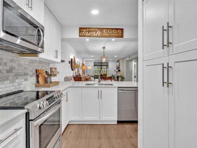 1489 Fairway Rd, Pembroke Pines, FL 33026 - kitchen with stainless steel appliances, a sink, light wood finished floors, white cabinetry, and tasteful backsplash